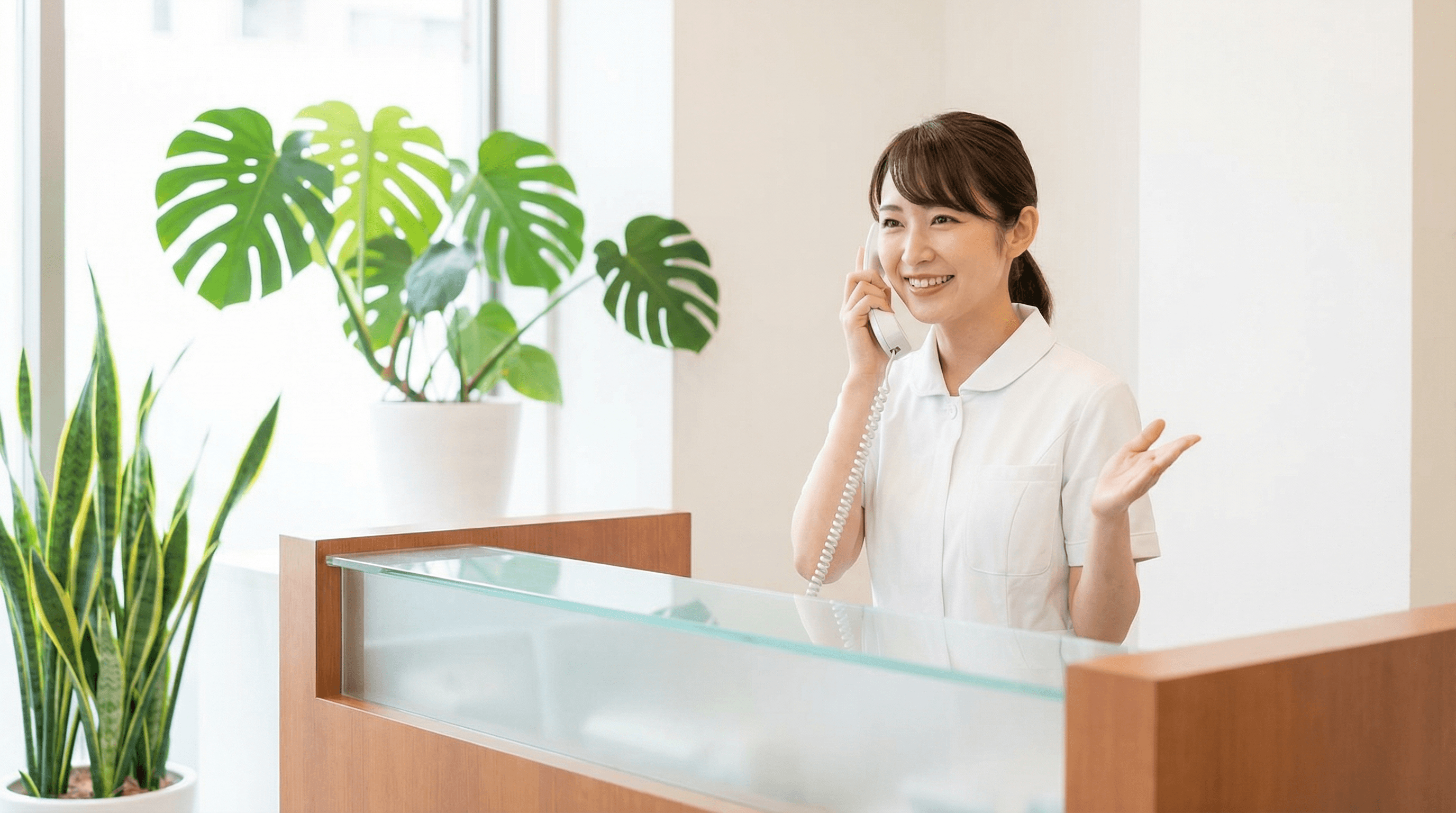 受付スタッフが笑顔で電話対応している様子
